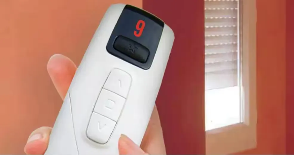 Hand holding a Somfy remote control for electric roller shutters